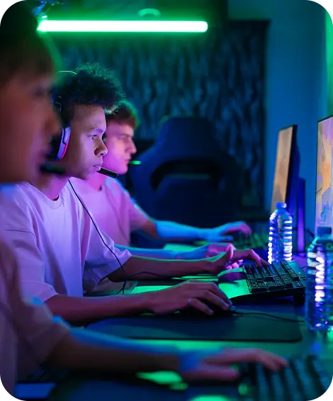 Een groep esports-spelers die op gaming-pc’s spelen, met een headset op en vol concentratie tijdens een spannende multiplayer-wedstrijd in een met neon verlichte omgeving.