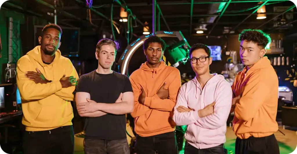Een professioneel esports-team staat bij elkaar in een gamingarena, gekleed in bij elkaar passende outfits en zelfverzekerd poserend onder neonverlichting.
