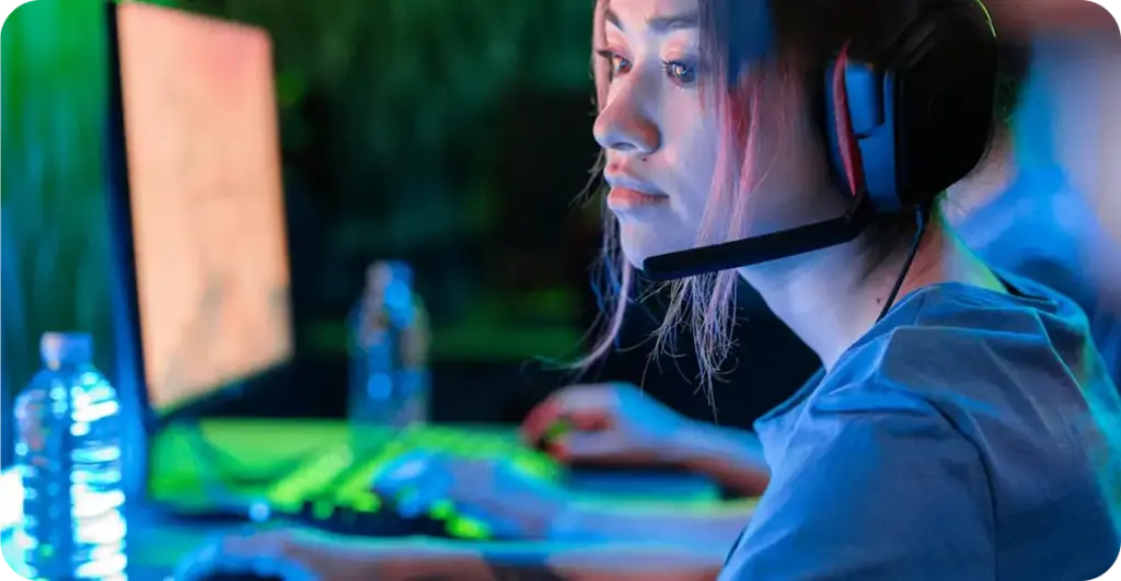 Een geconcentreerde vrouwelijke gamer met een headset op, spelend op een pc met kleurrijke verlichting, volledig opgaan in een esports-omgeving.